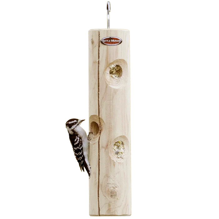 Hanging cedar suet log feeder with a downy woodpecker feeding from recessed suet holes.