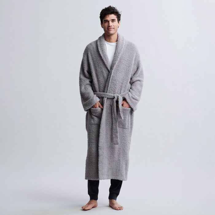 dove gray, A man wearing a plush, light gray terry cloth bathrobe with a tie belt, standing against a light gray studio background.