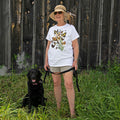 Butterflies of North America T-Shirt: Woman with sun hat standing beside a black dog in grass, holding a strap.