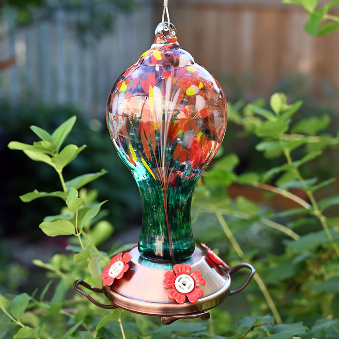 Color Infusion Glass Hummingbird Feeder with hand-blown multicolored glass and copper base, featuring four red flower-shaped feeding ports for easy nectar access.