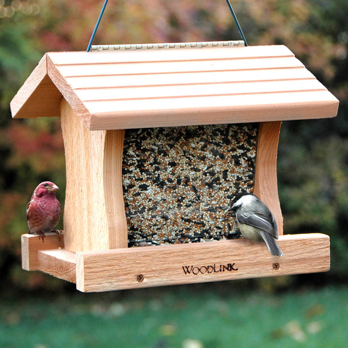 Deluxe Cedar Hopper Feeder with two birds feeding; features two feeding trays, clear panels for seed level view, and a sturdy cedar build.