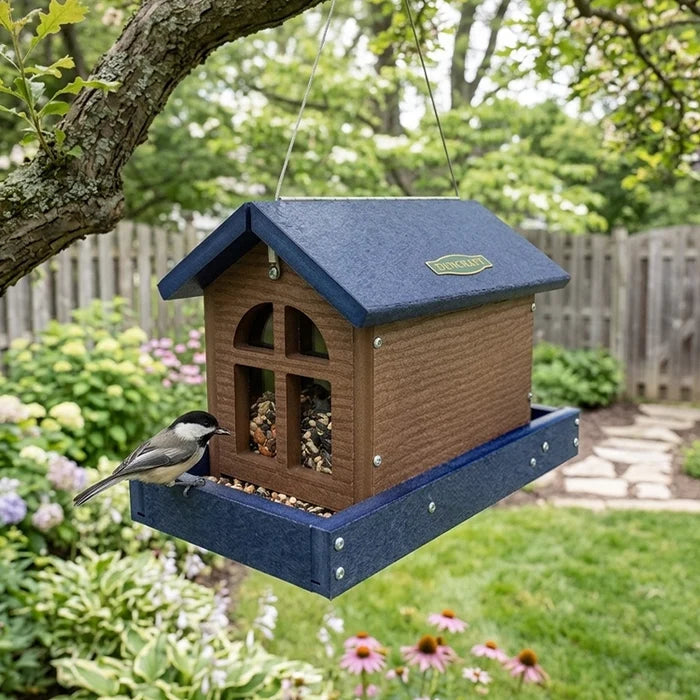 Barn bird feeder with seed and a bird hanging in the backyard showing the front view.