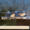 Duncraft Classic III Window Bird Feeder with birds feeding, clearview plastic, roof, perching space, and three suction cups attached to a window.