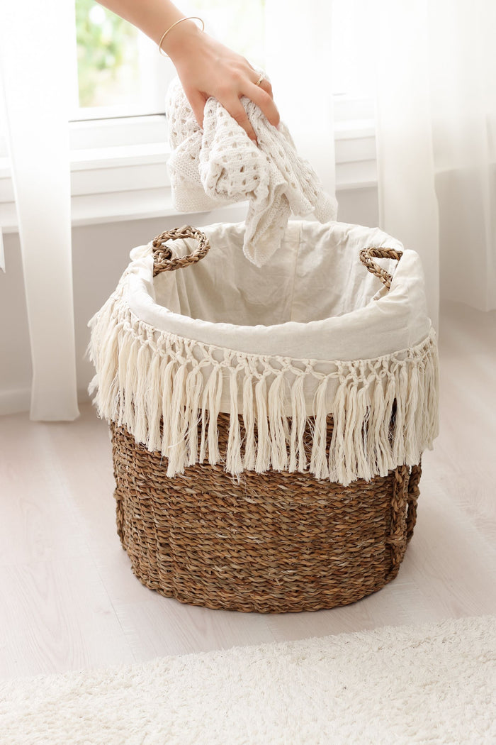 Fringed basket holding folded textiles on a carpet