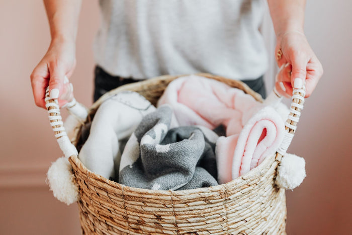 Hands lifting laundry from a woven seagrass basket
