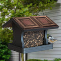 Modern Farmhouse Vintage Wood with Tin Roof Hopper Feeder showcasing a bird perched on it. Feeder design supports various birds and holds up to 4 lbs of seed.