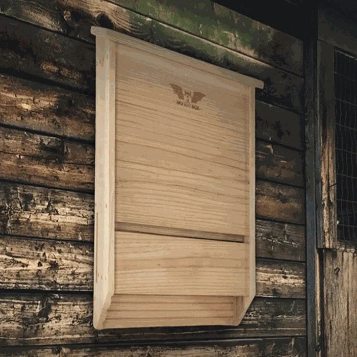 Cedar bat house mounted on the side of a brown barn.