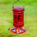 Water Cooler Style Glass Hummingbird Feeder with green hummingbirds at feeding ports, designed for easy cleaning and refilling, enhances backyard with elegant, functional design.