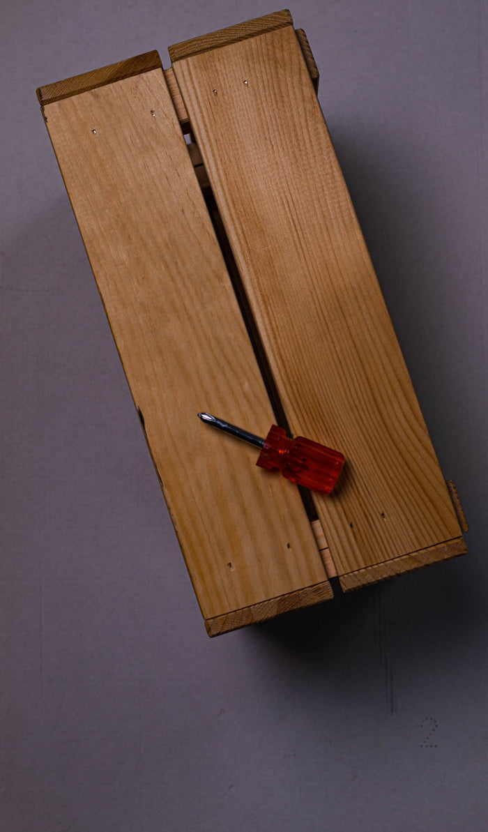 Hinged wooden box against a coloured background